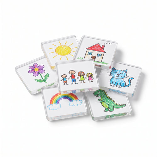 Seven clear acrylic Memora frames, each holding a child's crayon drawing: a sun, a house, a flower, a family, a cat, a rainbow and a dinosaur